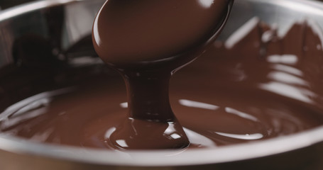closeup pouring melted dark chocolate from spoon - Powered by Adobe