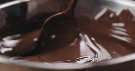 closeup stirring molten dark chocolate with spoon