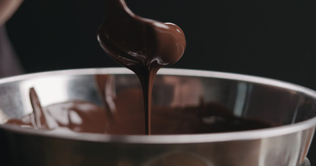 closeup pouring melted dark chocolate from spoon