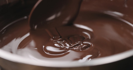 closeup stirring melted dark chocolate with spoon