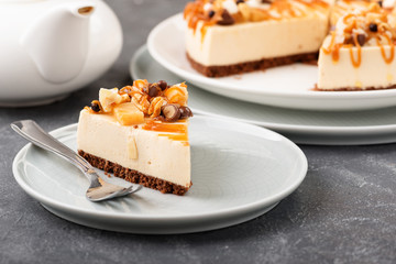 Homemade cheesecake slice with nuts and caramel sauce topping.