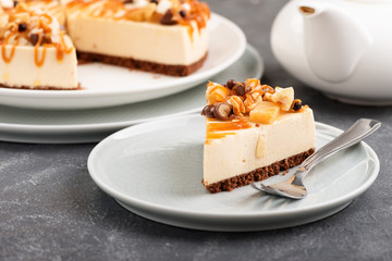Homemade cheesecake slice with nuts and caramel sauce topping.