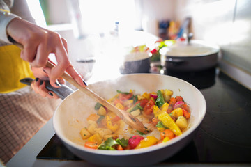 Close up of woman hands mixing food in cooking pan.