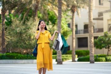 Fototapeta premium Asian girl on the phone with shopping bags