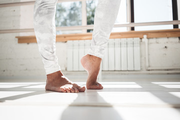 Closeup view on fit woman warming-up legs indoor white gym