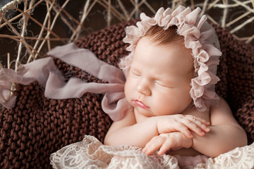 Sweet newborn baby sleeping.  Newborn girl 3 weeks old lying in a basket with knitted plaid. Portrait of pretty  newborn girl. Closeup image. Dark brown background