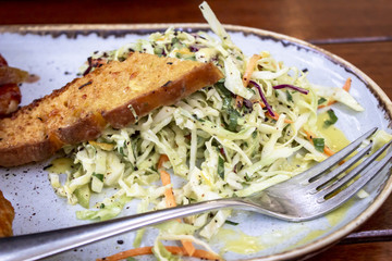 Close-up shoot of fresh salad on white plate at wooden table