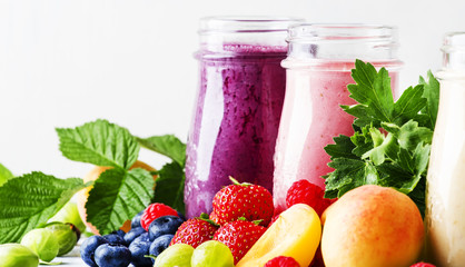 Healthy and useful colorful berry cokctalis, smoothies and milkshakes with yogurt, fresh fruit and berries on gray table, selective focus