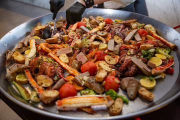Gourmet seafood Valencia paella with fresh langoustine, clams, mussels and squid on savory saffron rice with peas and lemon slices, close up view