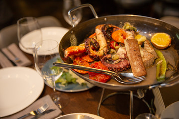 sea cocktail in a black plate. shrimp mussels, octopus, tuna, squid and lemon on a pan. seafood serving at restaurant