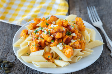 Penne pasta with pieces of fried pumpkin with onions and mozzarella