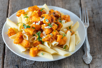 Penne pasta with pieces of fried pumpkin with onions and mozzarella