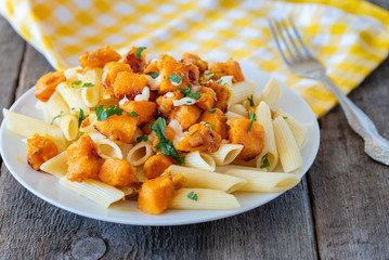 Penne pasta with pieces of fried pumpkin with onions and mozzarella