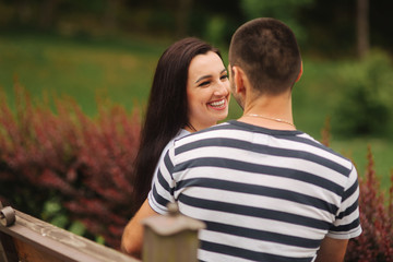 A guy and a girl enjoy each other in a romantic atmosphere and sits on the bench