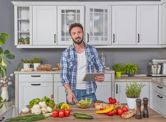 Man with digital tablet cooking dinner