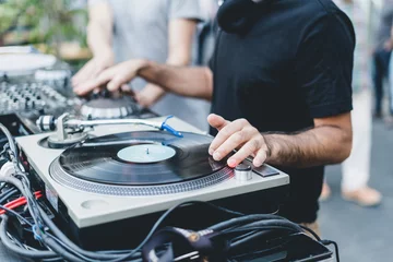 Fototapeten DJ mixing vinyl records on a turntable in a daily outdoor party. Focus on his hands © Lomb