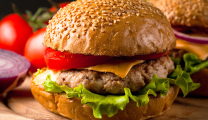 Close-up photo of home made hamburger with beer made of beef, onion, tomato, lettuce, cheese and spices. Fresh burger closeup on wooden rustic table with potato fries and chips.