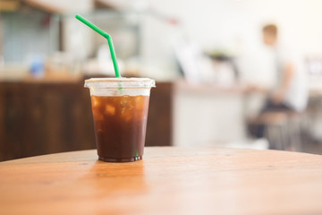Ice coffee americano in a glass on wood table with blur interior cafe background