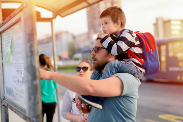 Tired father holding his son on his back while they are waiting for the transport. © Dusan Petkovic