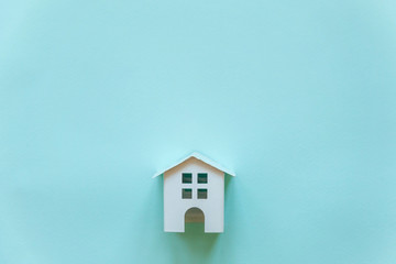 Obraz na płótnie Canvas Simply flat lay design with miniature white toy house on blue pastel colorful paper trendy background. Mortgage property insurance dream home concept. Flat lay, top view, copy space
