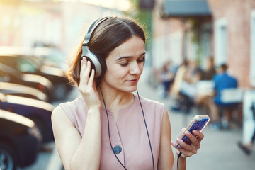 pretty woman listening to music with her headphones and mobile phone in the street