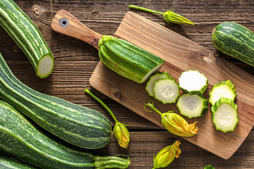 Fresh zucchini and slices of zucchinis on wooden table. Sliced courgette, healthy vegan diet or...