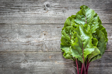 Farm fresh vegetables - green leaves of beet, bunch on wooden background