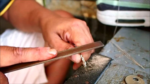 Close up video of the hands of a locksmith duplicating a key for a customer