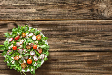 Healthy diet. Vegetable Fresh salad with arugula leaves, tomato, radish and seeds. Dietary appetizer or lunch on plate, vegetarian food concept.
