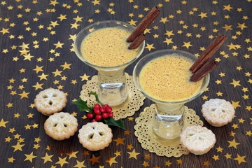 Christmas eggnog drink with traditional mince pies, gold star decorations and winter holly berries on rustic oak background. Festive theme.