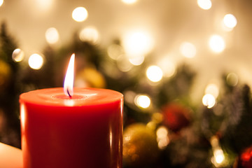 Christmas candles on the background of branches of a Christmas tree and glowing garlands