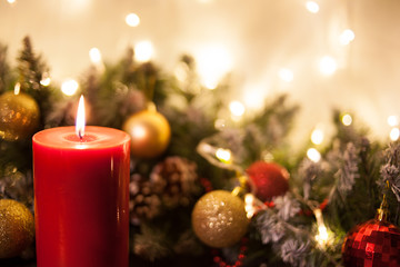 Christmas candles on the background of branches of a Christmas tree and glowing garlands