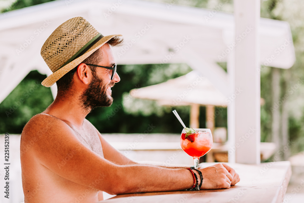 Sticker Young man enjoying cocktail in a beach bar