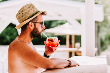 Young man enjoying cocktail in a beach bar