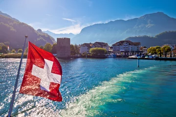 Foto auf Leinwand Vierwaldstättersee-Boot, das aus dem Dorf Stansstad mit Schweizer Flagge fließt © xbrchx