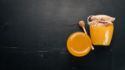 Honey in a jar on a black wooden background. Free space for text. Top view.