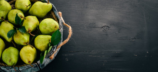 Fresh green pear. Assortment of pears in a wooden box. On the black table. Free space for text. Top view.