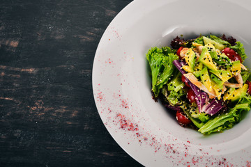 Vegetable salad with chicken fillet and avocado. On a wooden background. Free space for text. Top view.