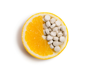 Tablets with vitamins in an orange slice. Isolated on white background.