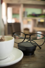 cup of coffee and pair of glasses on lens in cafe