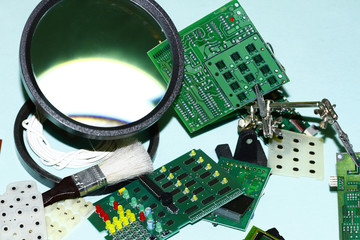 Electronic components printed circuit boards with magnifying glass in the foreground.
