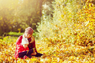 mother teaching daughter in autumn park, Mother teaching daughter to read.