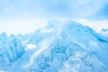 beautiful winter landscape with snow covered peak of Caucasus mountain, Dombaj over clouds, Russia,...