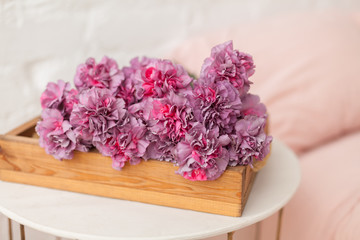 Obraz na płótnie Canvas Pink fluffy carnation flowers bouquet on the wooden tray. Big empty cup