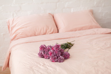 Pink and violet fluffy carnation flowers bouquet on the bed. Pink bedding