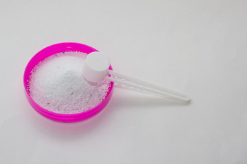 Stain remover and bleach on a red cover with a measuring spoon on a white background, close-up, stain remover