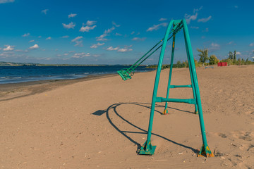 Beautiful landscape with swings on empty sandy beach