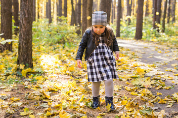 Fall, childhood, people concept - little happy girl walking in autumn park