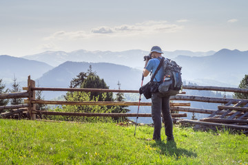 Male landscape photographer during hiking in the rural area at the mountains. Taken during sunny spring evening at Carpathian mountains, Ukraine. Concept of travel photography lifestyle.