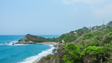 Fototapeta na wymiar huts in front of a tropical beach with turquoise water at tayrona natural park